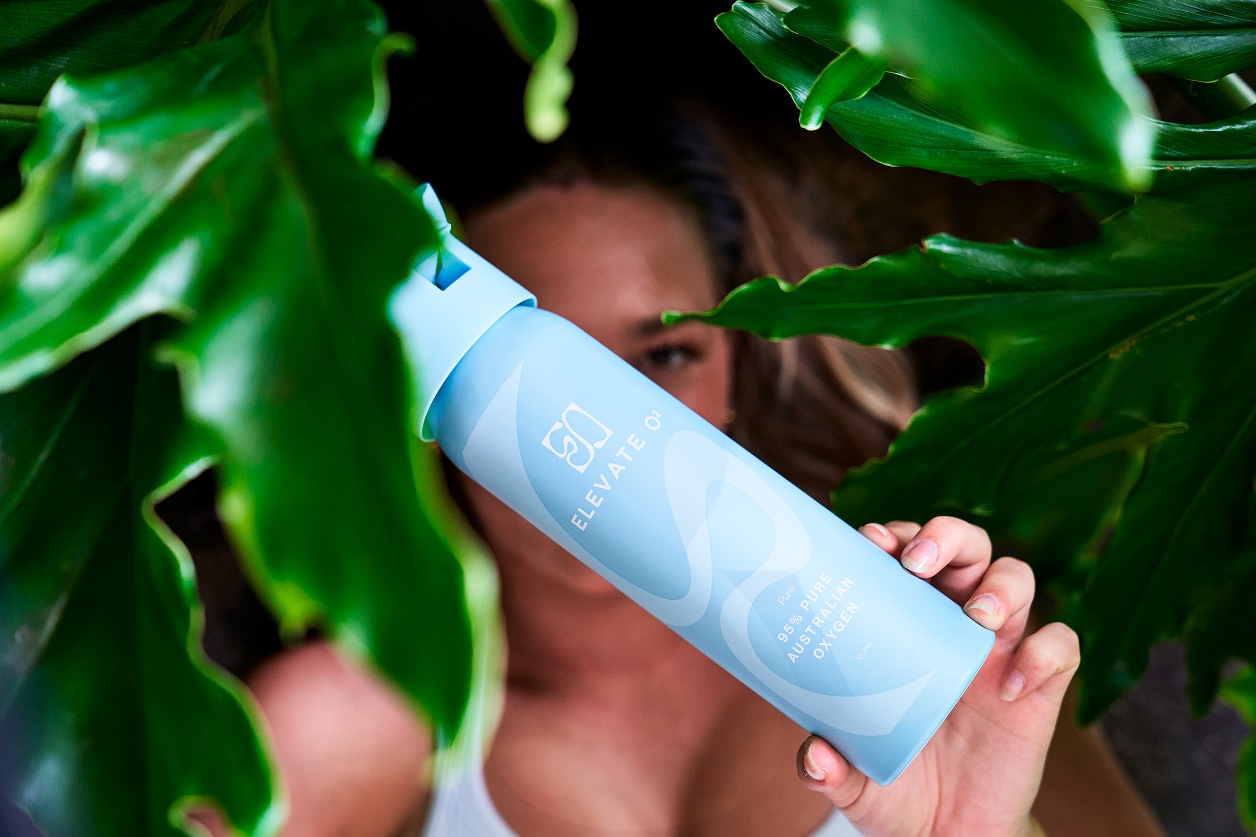 model holding elevate o2 canister on a leafy background